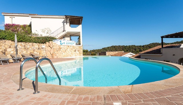 Complex surrounded by greenery with pool